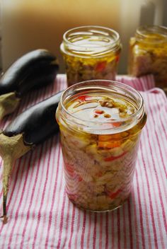 three jars filled with food sitting on top of a red and white striped table cloth