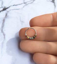 a person's hand holding a small ring with beads on the inside of it