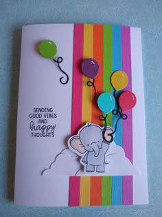 an elephant holding balloons on top of a rainbow colored card with the words sending good wishes and happy thoughts