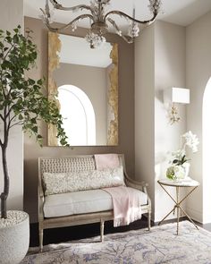 a living room with a couch, mirror and potted plant on the side table