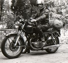 a man riding on the back of a motorcycle wearing a helmet and holding a bag