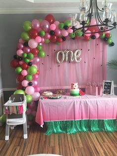 a pink and green birthday party with balloons, streamers, cake table and decorations