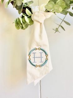 a white cloth bag with a monogram on it hanging from the side of a wall