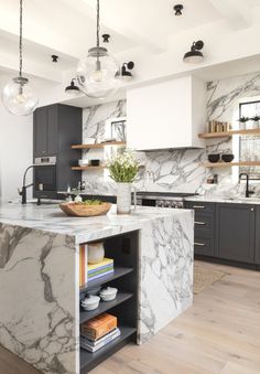 a large kitchen with marble counter tops and black cabinetry, along with wooden flooring