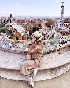 a woman sitting on top of a tiled roof looking at the city in the distance