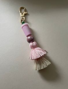 a pink keychain with a tassel hanging from it's side on a white surface