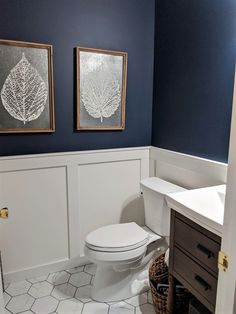 a white toilet sitting in a bathroom next to a sink and mirror on a wall