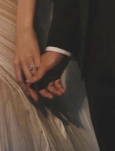 a close up of a person wearing a wedding ring on their finger and holding another persons hand