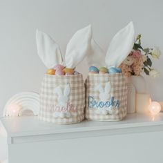 two easter baskets with bunny ears and personalized candy in them sitting on a shelf