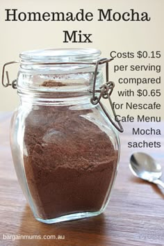 a jar filled with dirt sitting on top of a wooden table next to a spoon