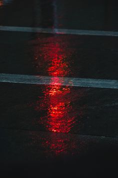 a red light reflecting off the wet pavement