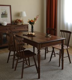 a dining room table and chairs in front of a window