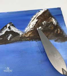 a pair of scissors is sitting on top of a piece of art that looks like mountains