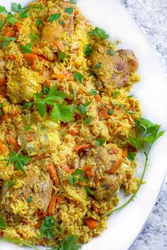 a white plate topped with rice covered in meat and veggies on top of a table