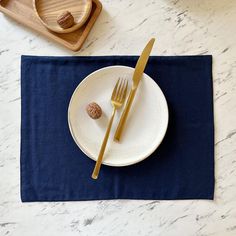 a white plate topped with a fork and knife next to a blue napkin on top of a table