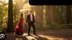 a young man and woman holding hands in the woods with sunlight streaming through trees behind them