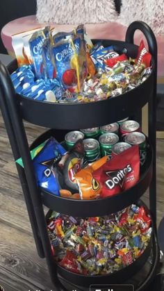 a three tiered tray with drinks and snacks on the bottom is sitting on a wooden floor