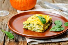 a brown plate topped with an omelet covered in cheese and spinach leaves