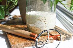 a glass jar with some liquid in it on a cutting board next to a knife