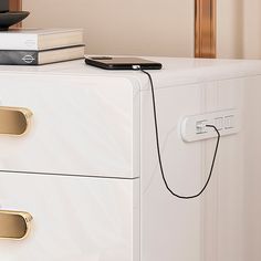 a white filing cabinet with two drawers and a phone on the top one drawer is plugged in