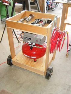 a small workbench with some tools on it and red hoses attached to the cart