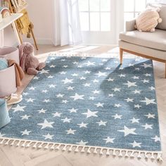 a blue rug with white stars and pom poms on it in a living room