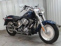 a blue motorcycle parked in front of a metal building with a white wall behind it