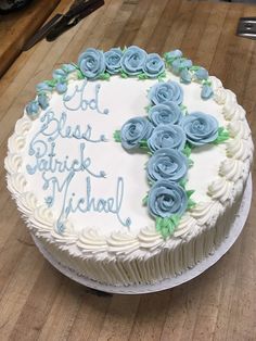 a white cake with blue frosting and roses on it sitting on a wooden table