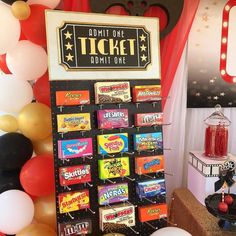 an assortment of candy on display in front of a ticket booth with balloons and streamers