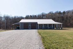 a large house sitting on the side of a road next to a field and forest