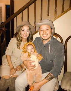 a man and woman sitting next to each other holding a baby in front of stairs