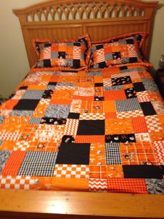 a bed with an orange and black quilt on it