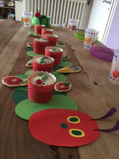 a long table topped with lots of cupcakes on top of paper cups and plates