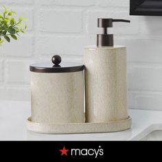 two white and brown bathroom accessories sitting on a counter next to a vase with flowers