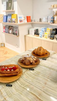 three wooden plates with food on them sitting on a table in front of bookshelves