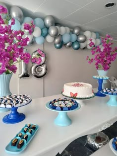 a table topped with cake and cupcakes next to balloons on the wall behind it