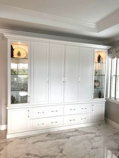 an empty room with white cabinets and marble floors