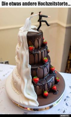 a wedding cake with chocolate frosting and strawberries on the top, topped by a bride and groom figurine