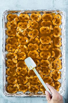 a person holding a spatula in front of a dish filled with caramelized bananas