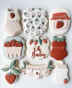 decorated cookies are arranged in the shape of baby's clothes and strawberrys on them