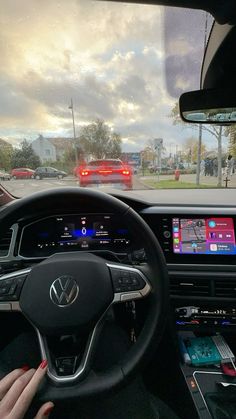 a woman driving a car on the road with her hands on the steering wheel and dashboard