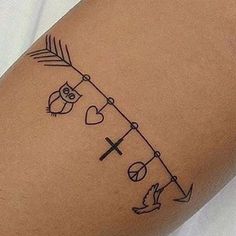 a tattoo on the leg of a woman with an arrow, cross and heart in it