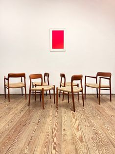 four chairs are lined up in front of a wall with a red square on it