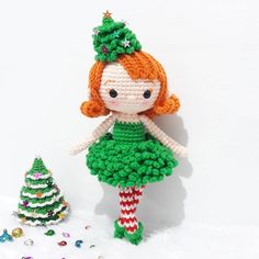 a crocheted doll is next to a christmas tree with decorations on the ground