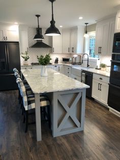 a large kitchen with an island in the middle and black appliances on both sides, along with white cabinets