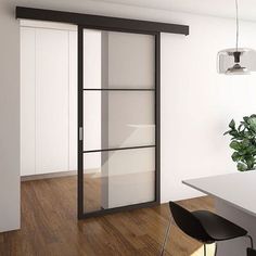 an empty room with white walls and wooden flooring is seen in this image, there are two black chairs near the table