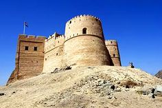 an old castle sits on top of a rocky hill in the middle of desert land