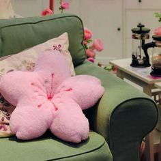 a pink teddy bear laying on top of a green chair next to pillows and flowers