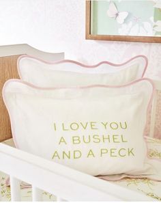 two pillows sitting on top of a white crib next to a framed picture and wall