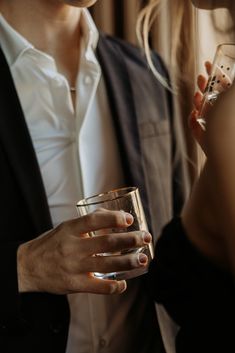 two people standing next to each other holding wine glasses